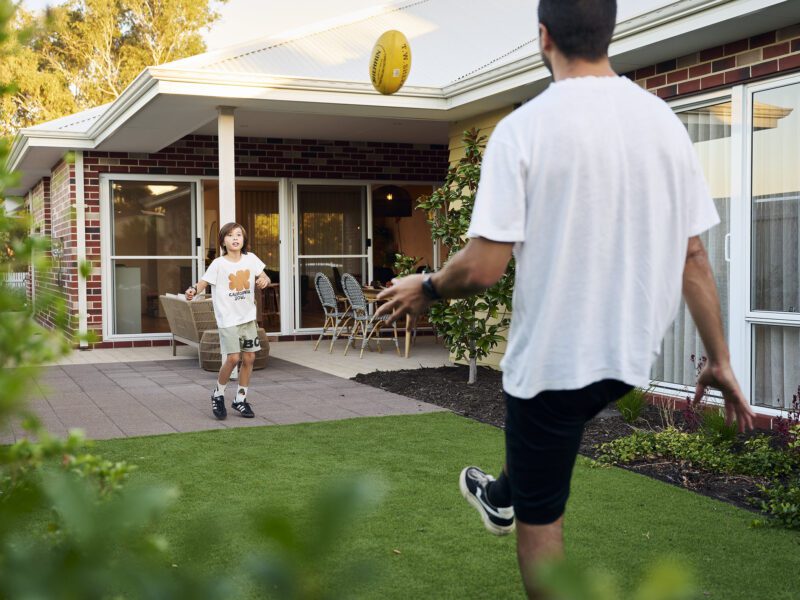 Father and son kicking football in their newly build WA Country Builders home backyard